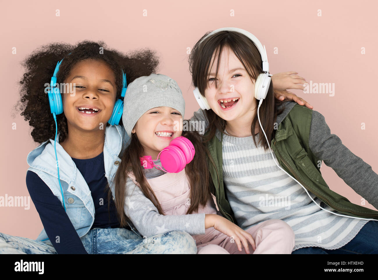 Group of Little Girls Studio Smiling Wearing Headphones and Winter Clothes Stock Photo