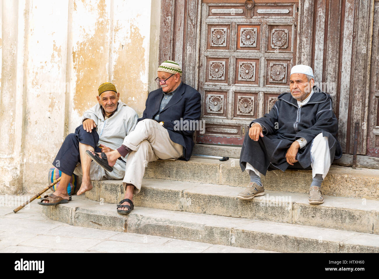 Fes, Morocco.  Three Old Men Resting on the Steps of the Andalusian Mosque, Fes El-Bali. Stock Photo