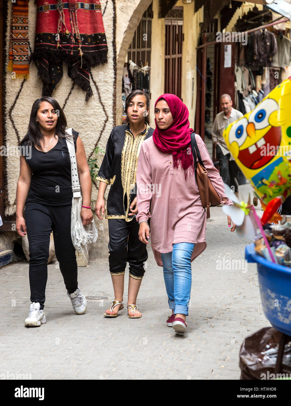Fes, Morocco.  Young Moroccan Women Walking in  the Medina, Tala'a Seghira Street, Fes El-Bali.  Modern Dress Styles. Stock Photo