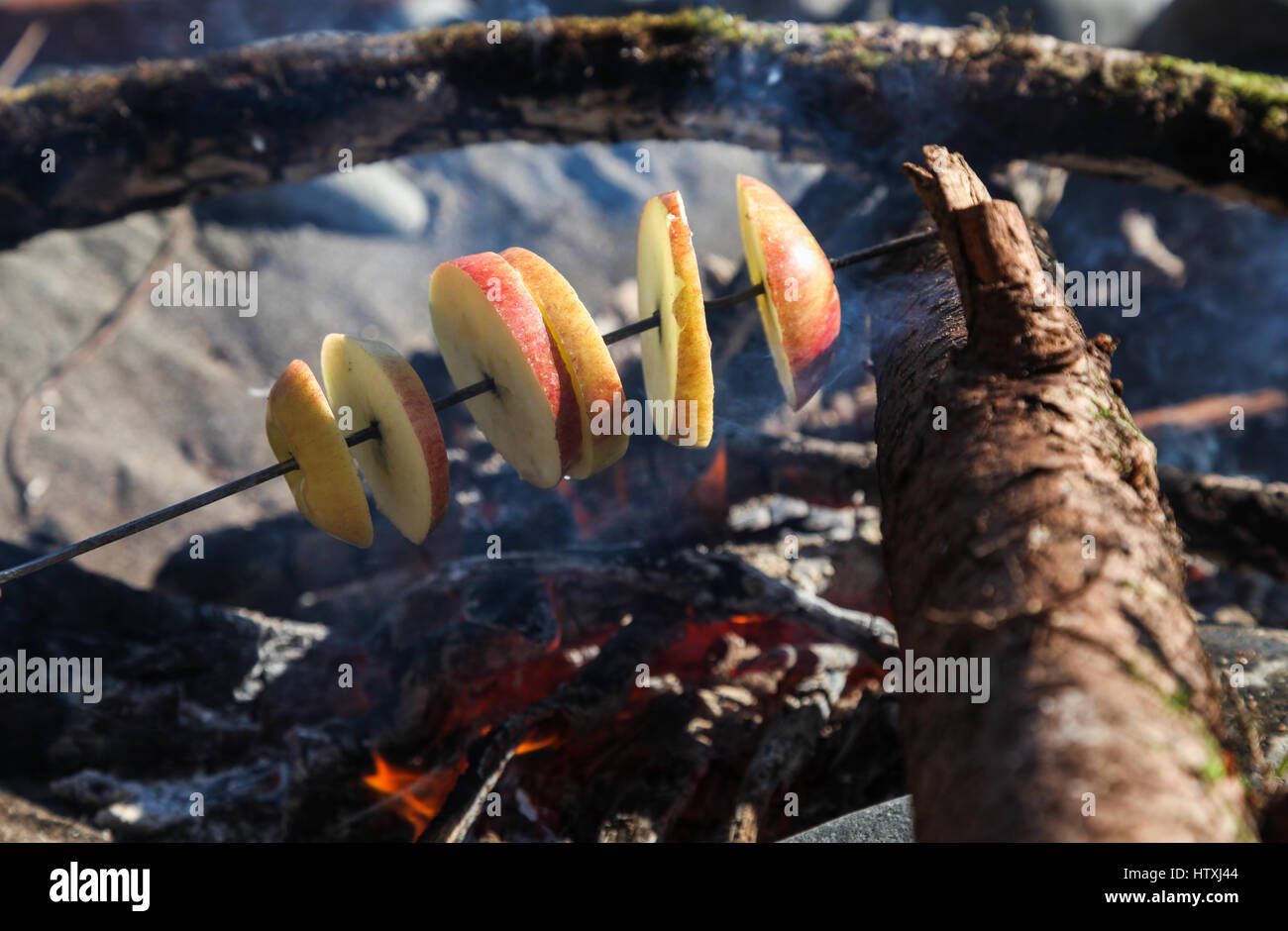 Roasting Apples over a beach fire Stock Photo