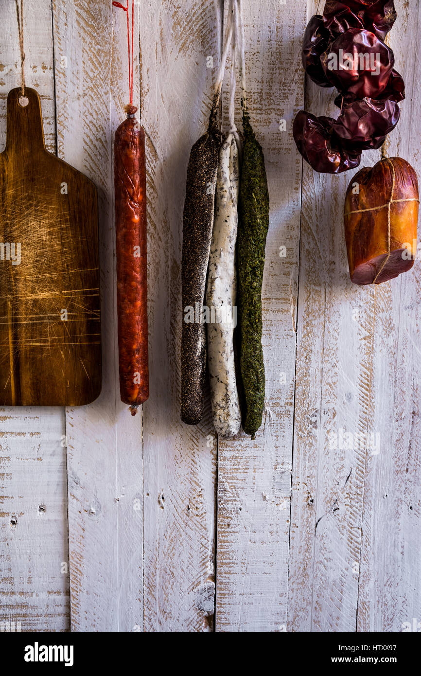 Charcuterie, variety of sausages hanging on hook, wood cutting board