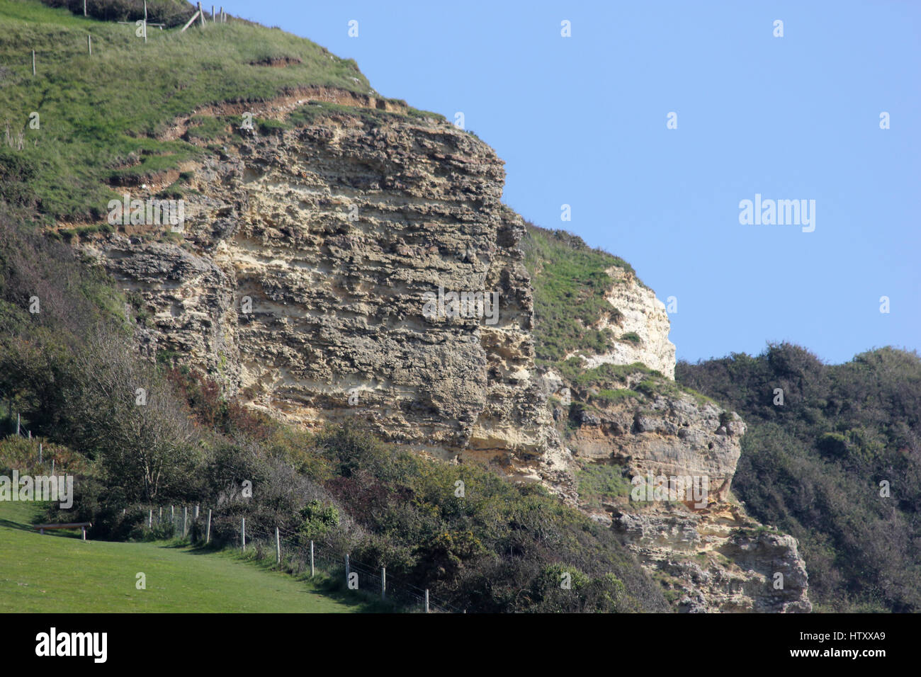 The upper greensand cliffs at Branscombe Mouth, Devon, showing part of the South West coast path national trail, on a sunny day with blue sky Stock Photo