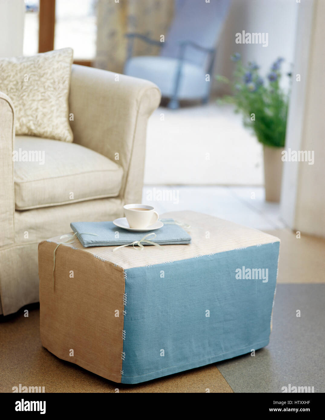 Pale blue and cream loose cover on an ottoman stool beside a cream