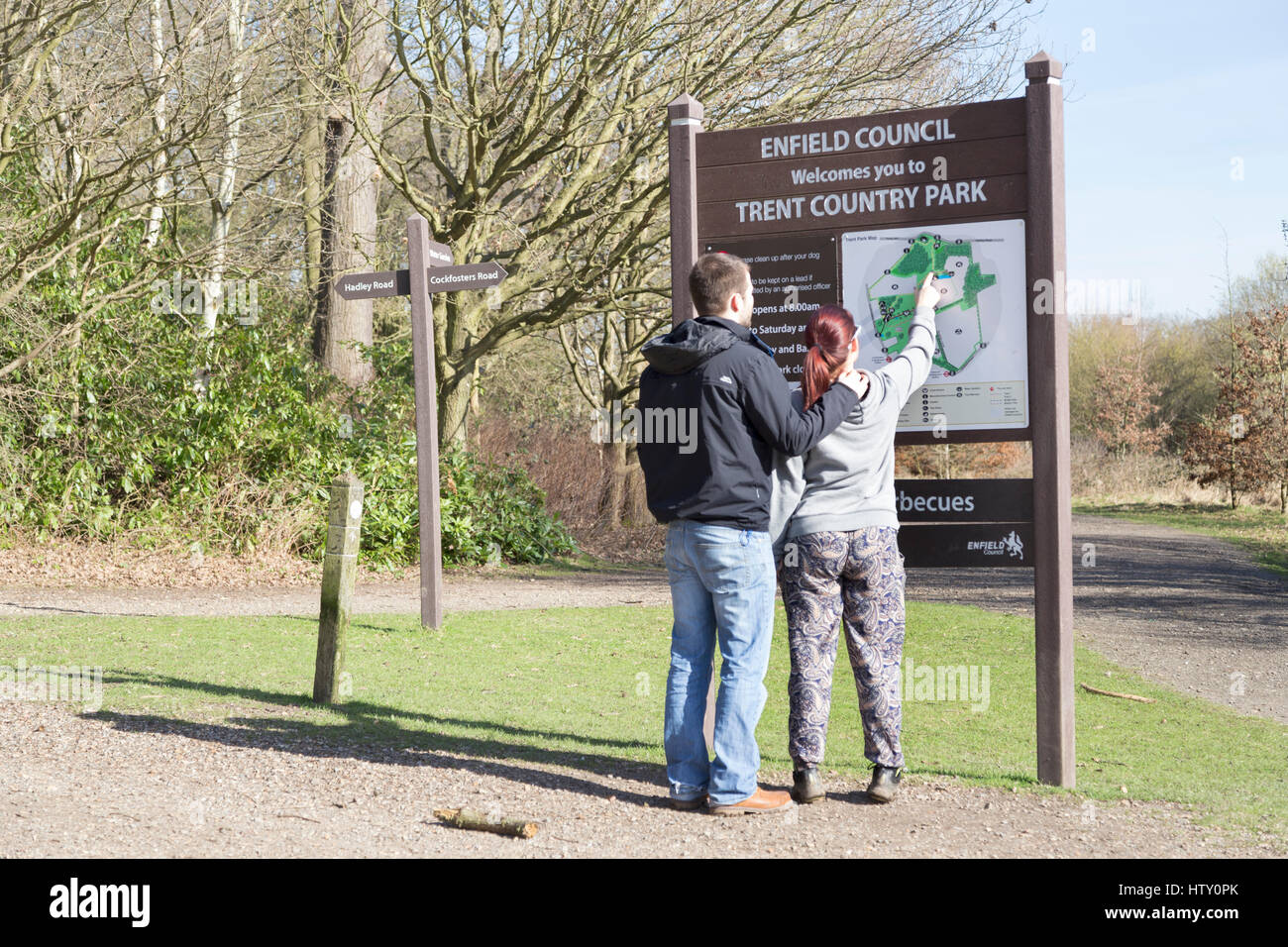 Two people looking at the map on an information board at Trent Country Park. Stock Photo