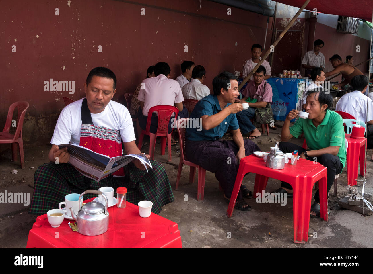 Middle aged men relax and  drink tea at a stall in Pansodan Street, Yangon, Yangon Region, Myanamar Stock Photo