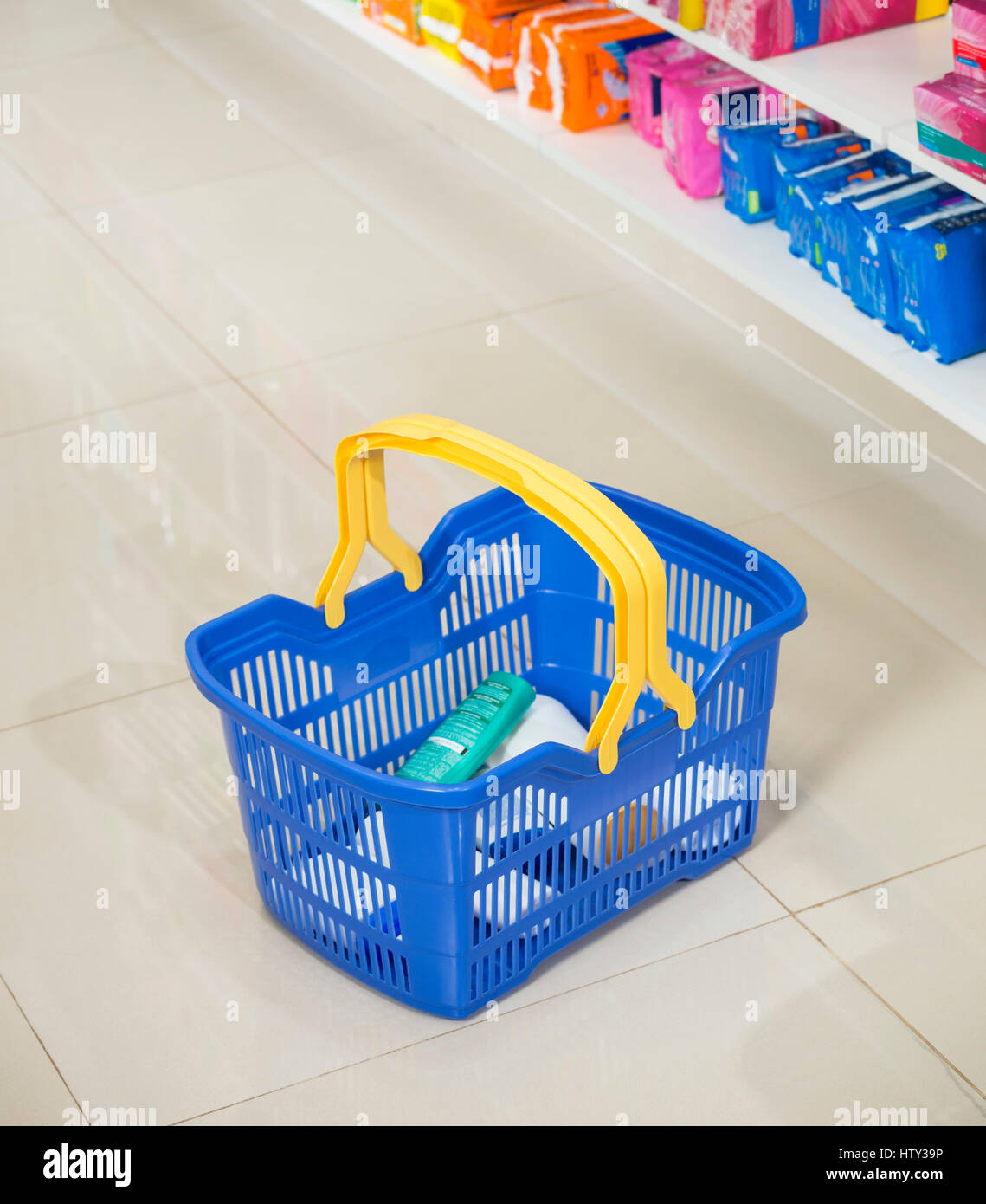 Shopping Basket On Aisle By Shelves In Pharmacy Stock Photo