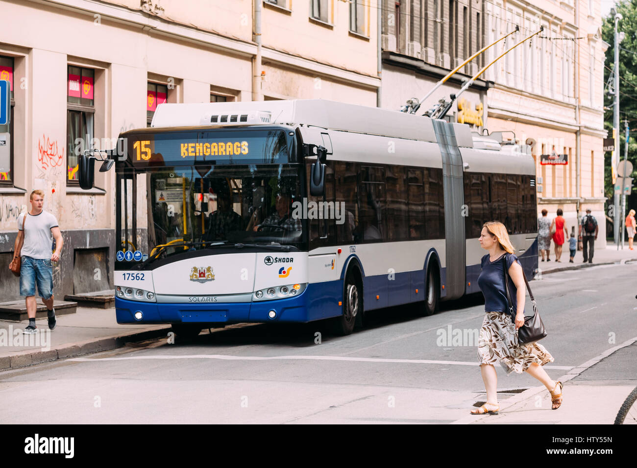 Riga, Latvia - July 1, 2016: Woman crossing road at a pedestrian crossing before staying public trolleybus. Stock Photo