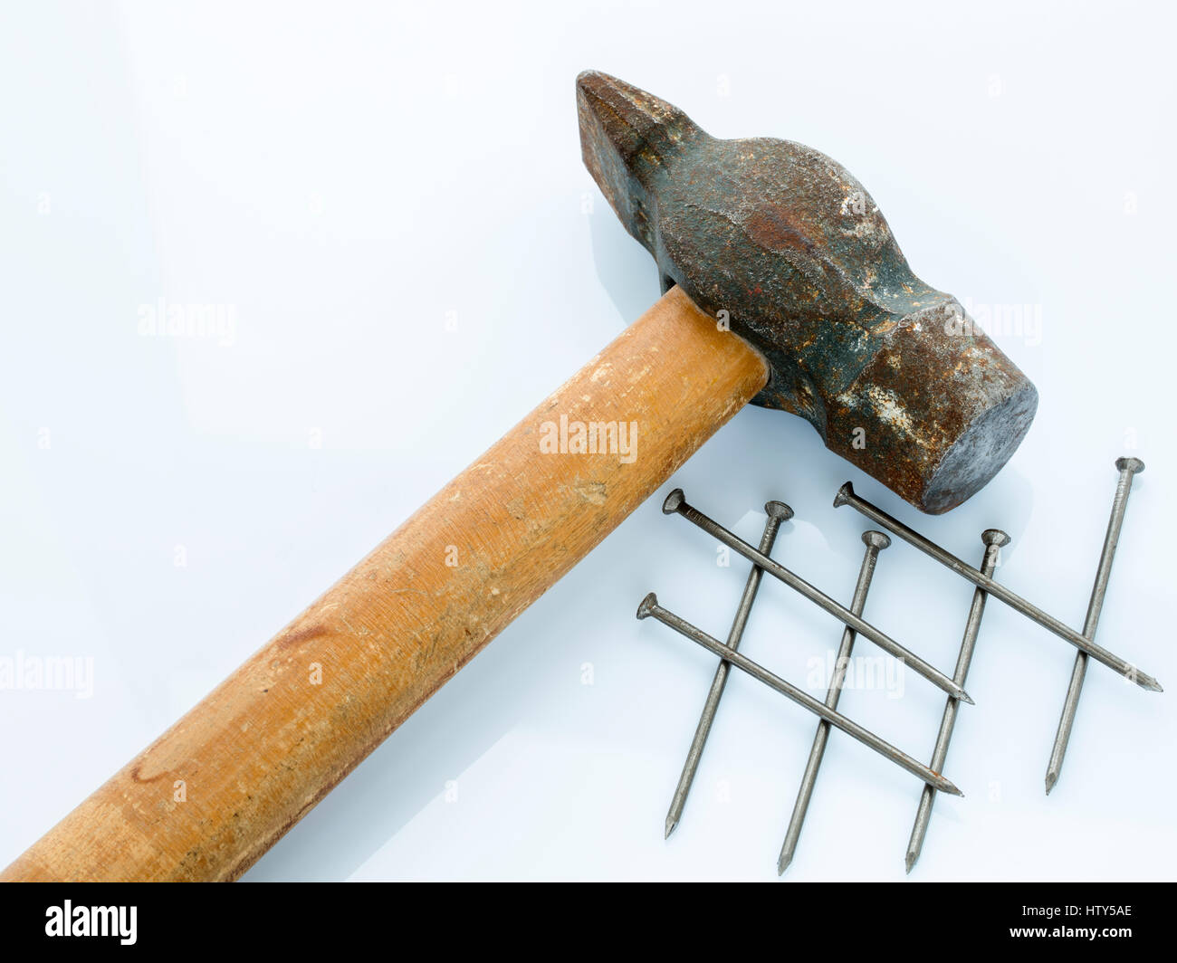 An old hammer with a wooden handle and a bunch of nails. Objects on a light background Stock Photo