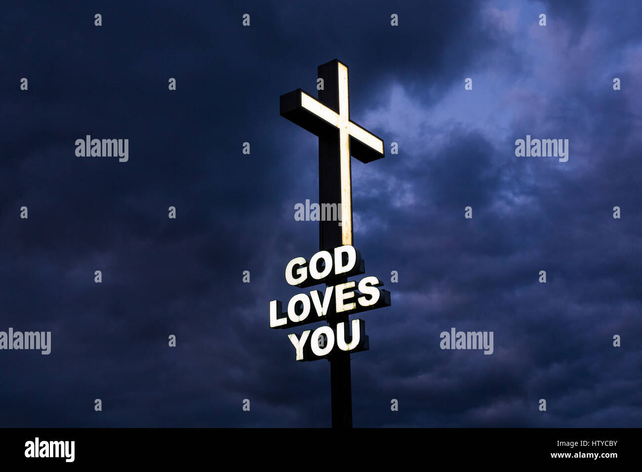 God Loves You sign with illuminated cross against a stormy sky Stock Photo