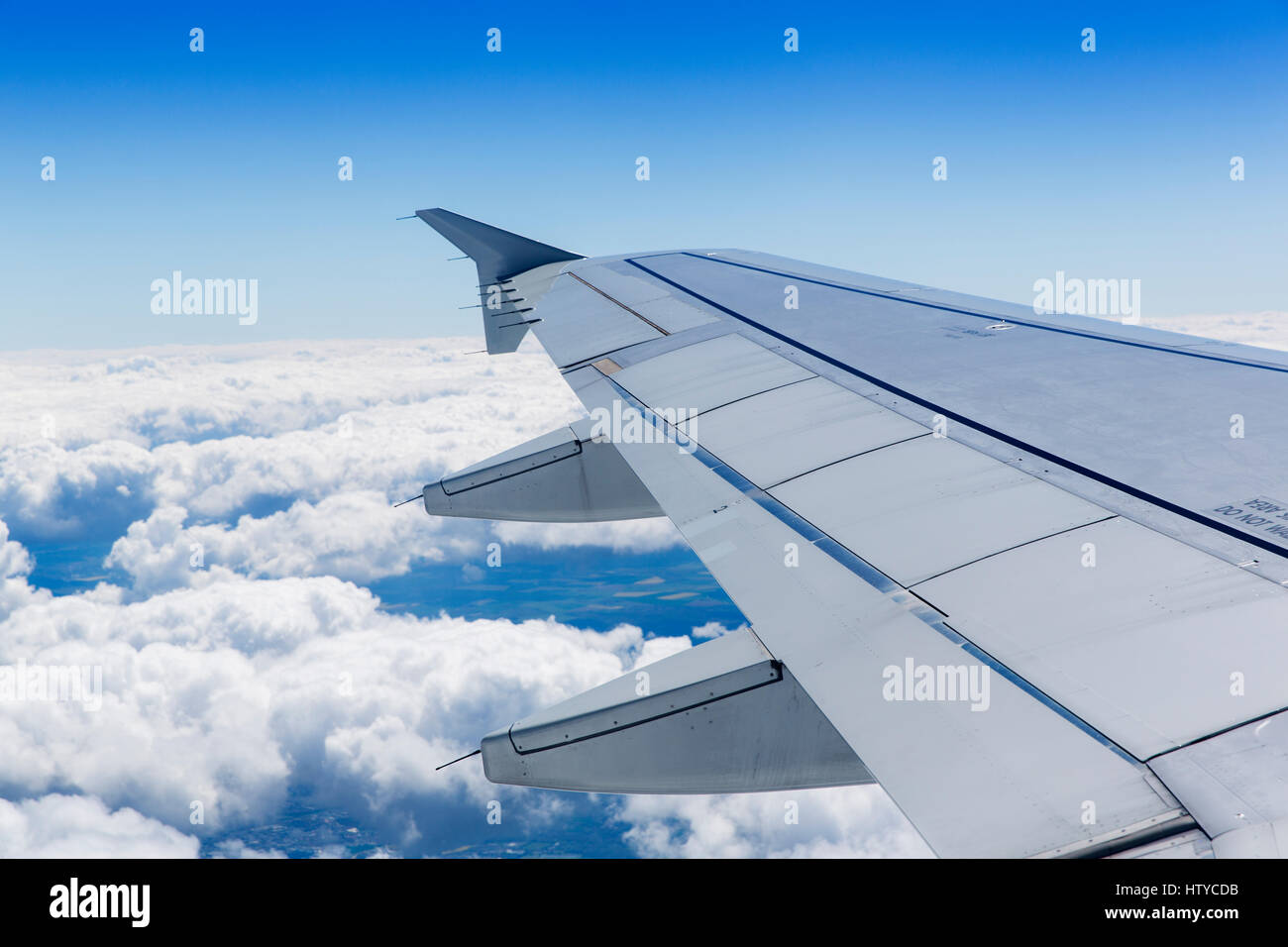 Airplane wing above the clouds and blue sky Stock Photo - Alamy