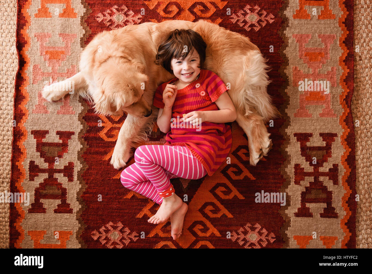 Overhead view of girl lying on floor with a golden retriever dog Stock ...