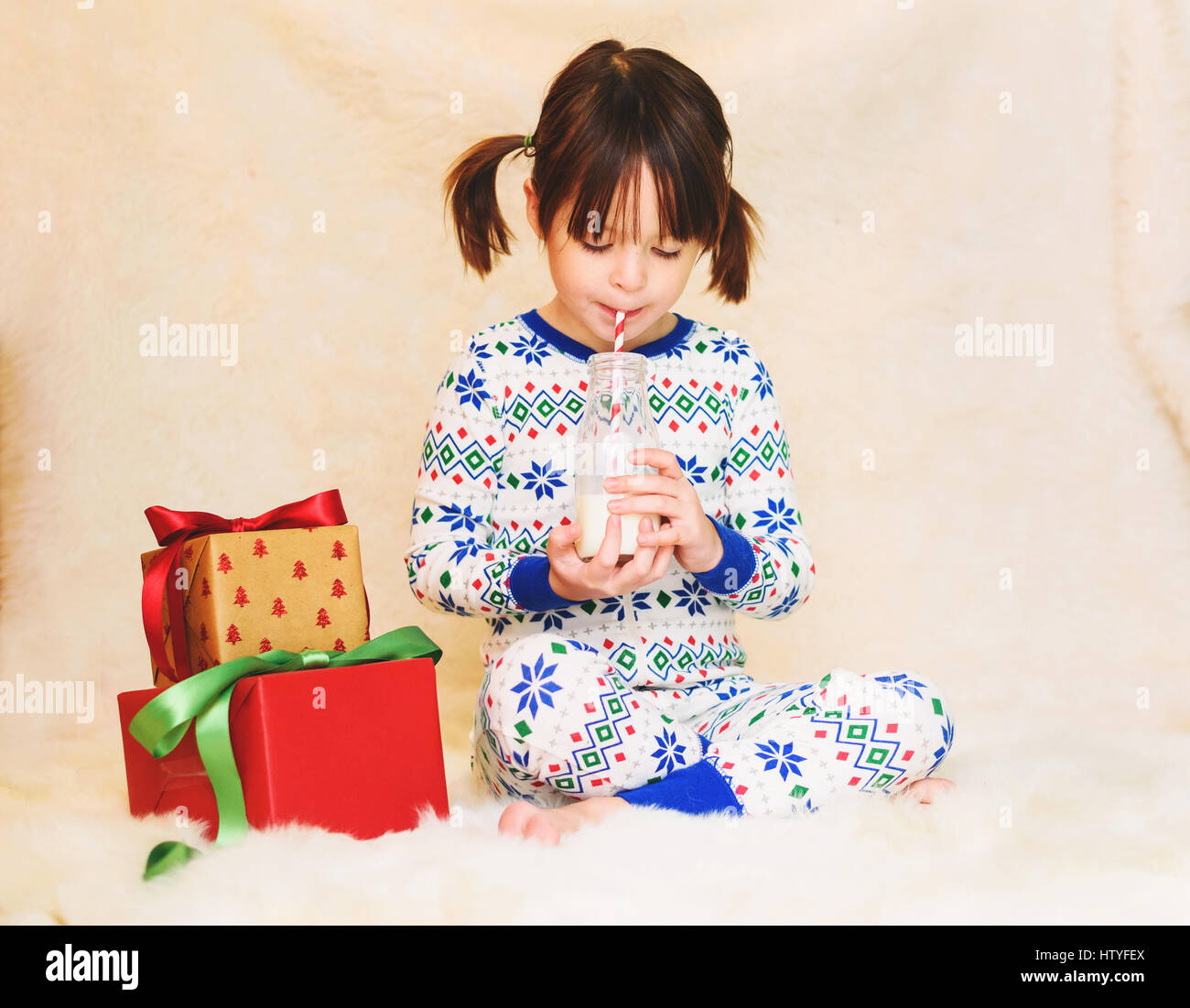 Girl with Christmas gifts drinking bottle of milk Stock Photo