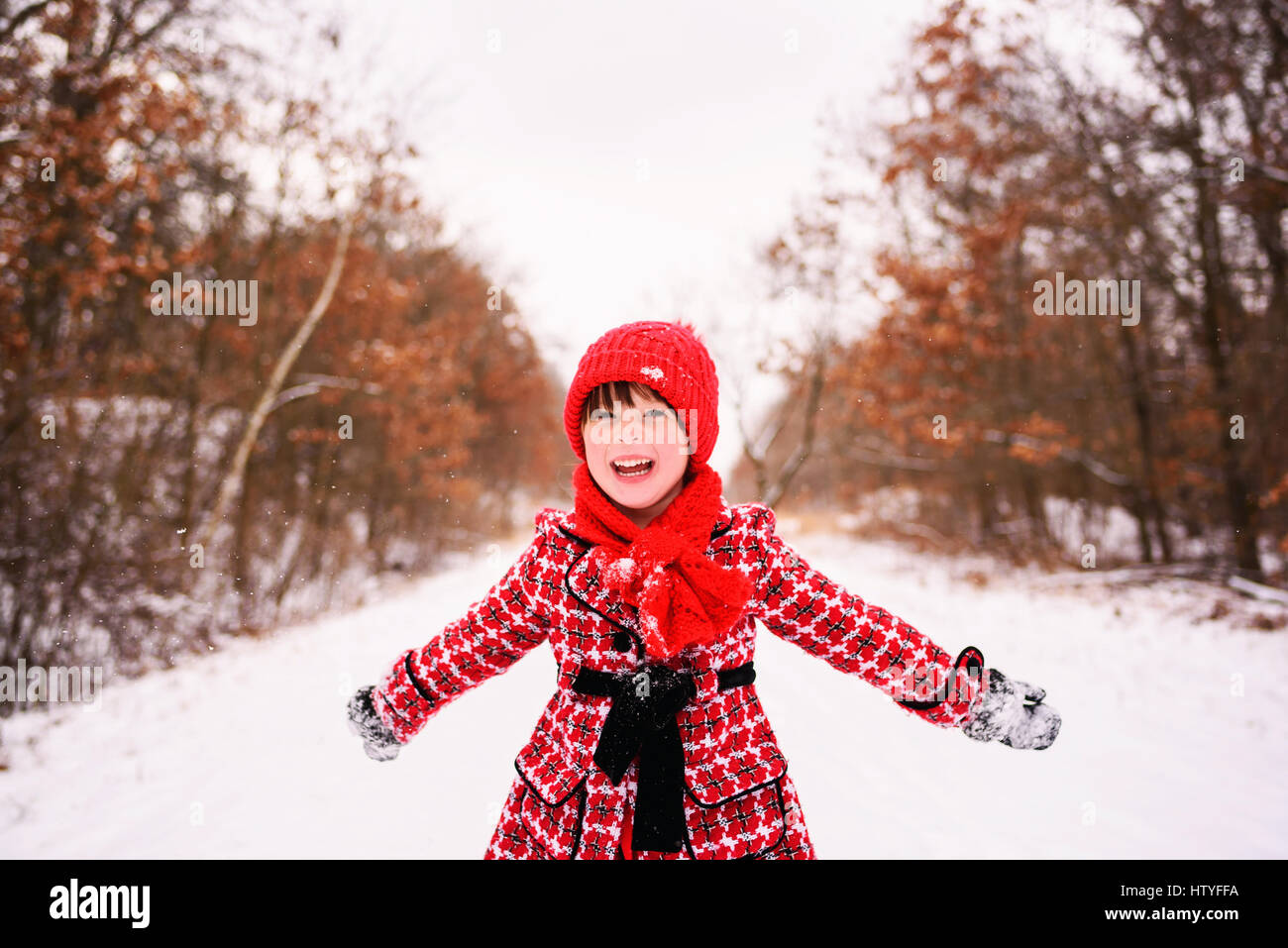 Girl standing in winter forest with arms outstretched Stock Photo