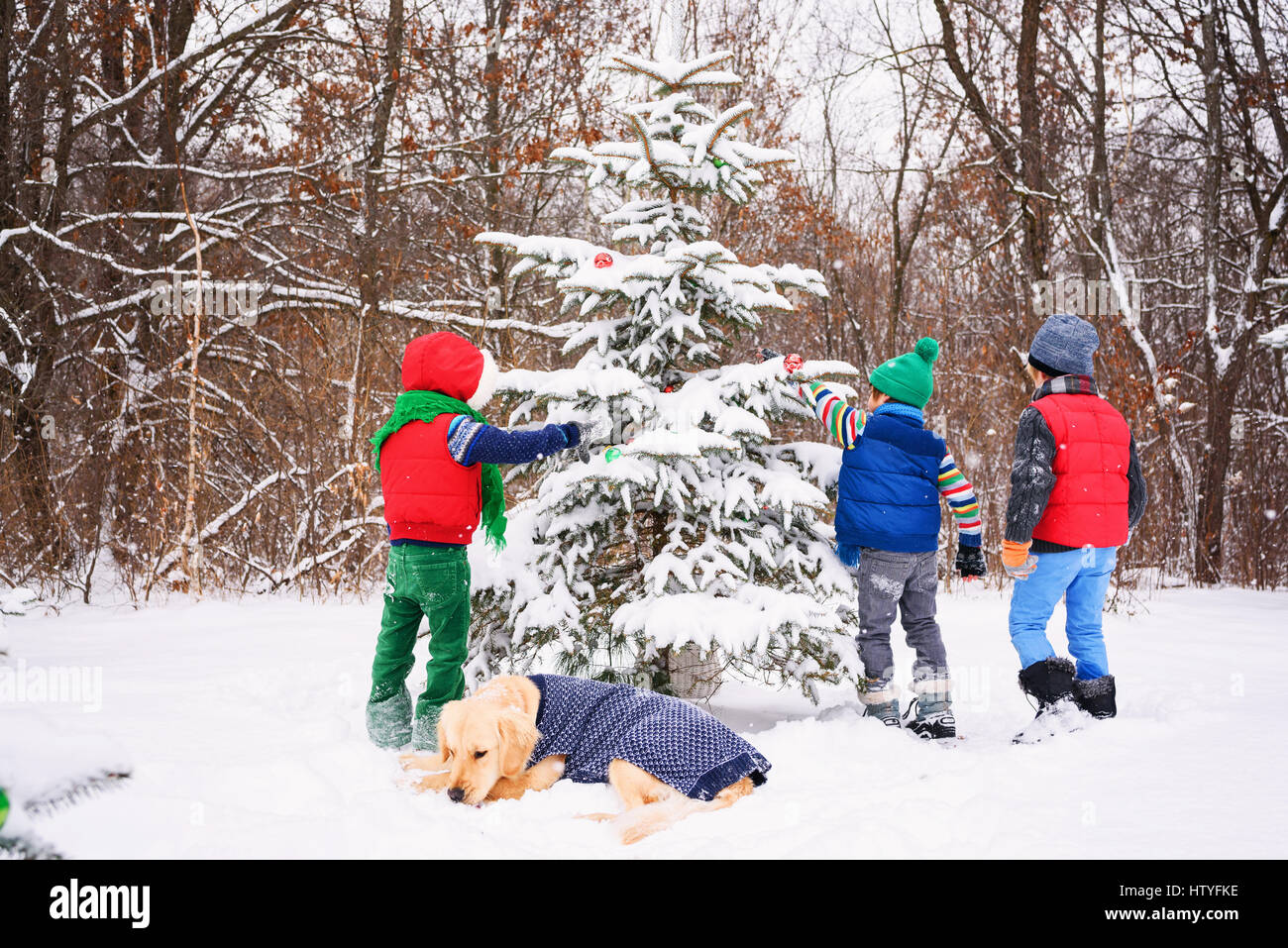 Three children decorating a Christmas tree in the garden with their