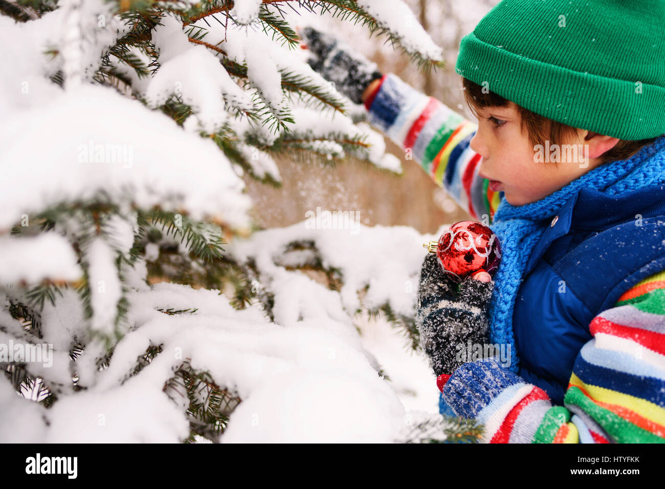 Boy decorating a Christmas tree in the garden Stock Photo