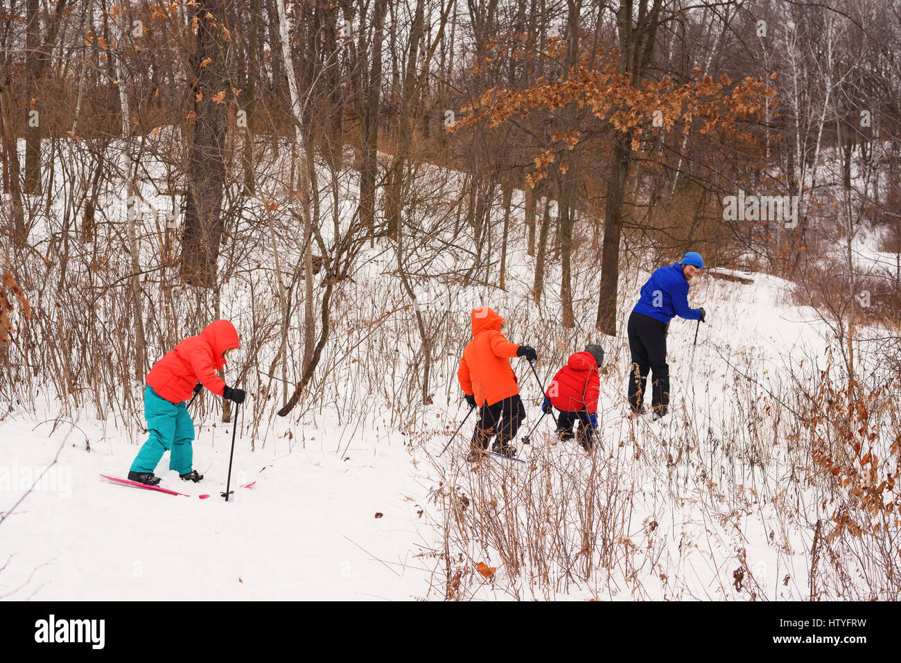 Father teaching three children to ski Stock Photo