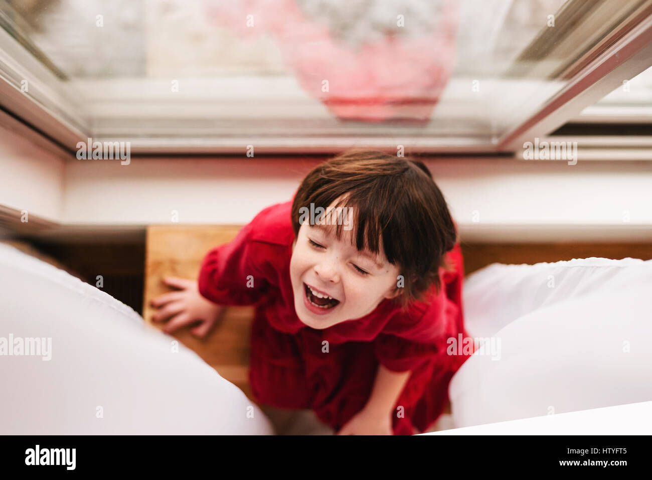 Overhead view of girl sitting by a curtain laughing Stock Photo