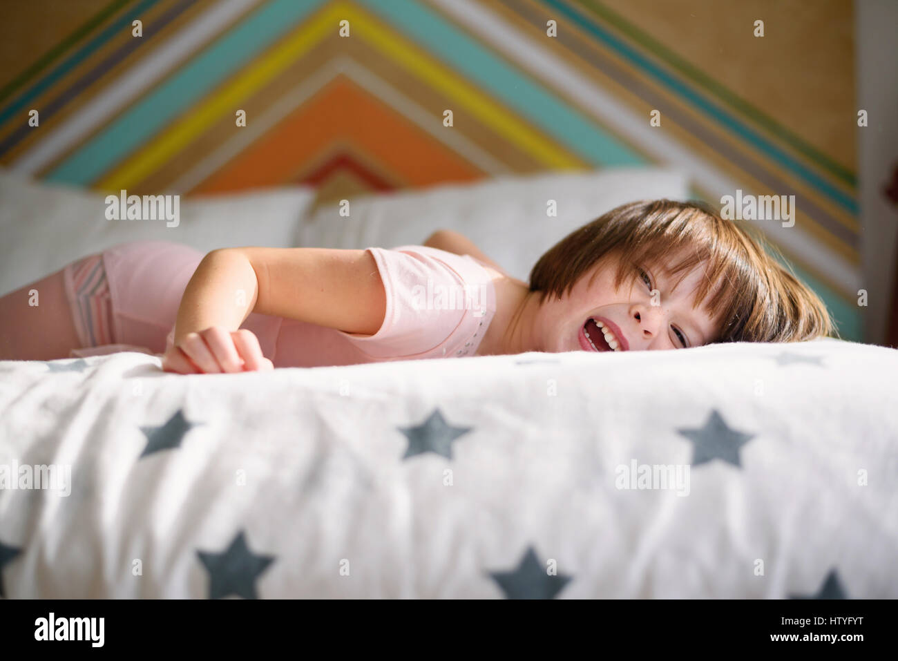 Happy girl lying on her bed laughing Stock Photo
