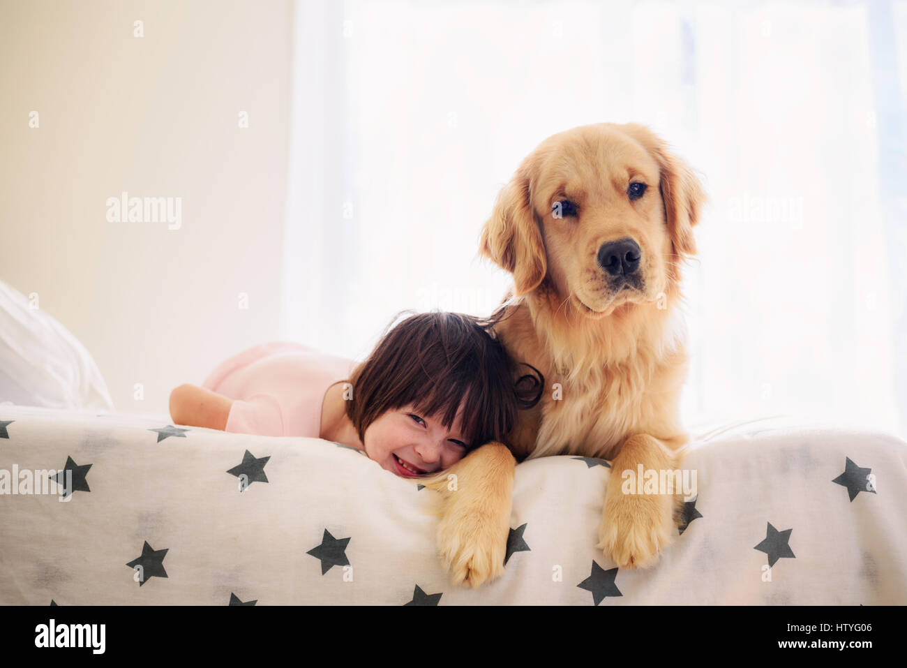 Girl lying on bed with golden retriever dog Stock Photo - Alamy