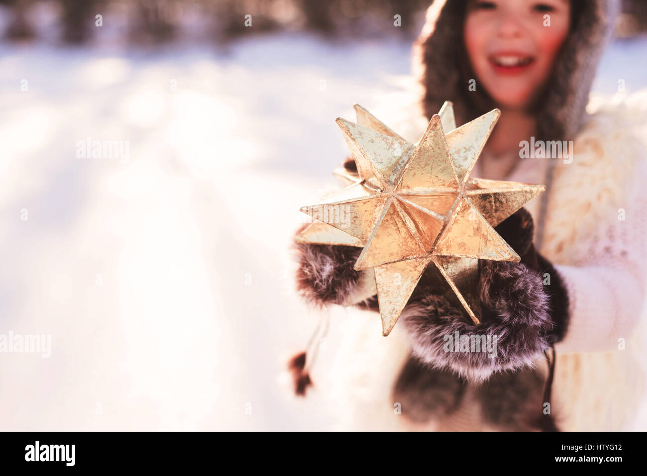 Girl in warm clothing holding a gold star Stock Photo