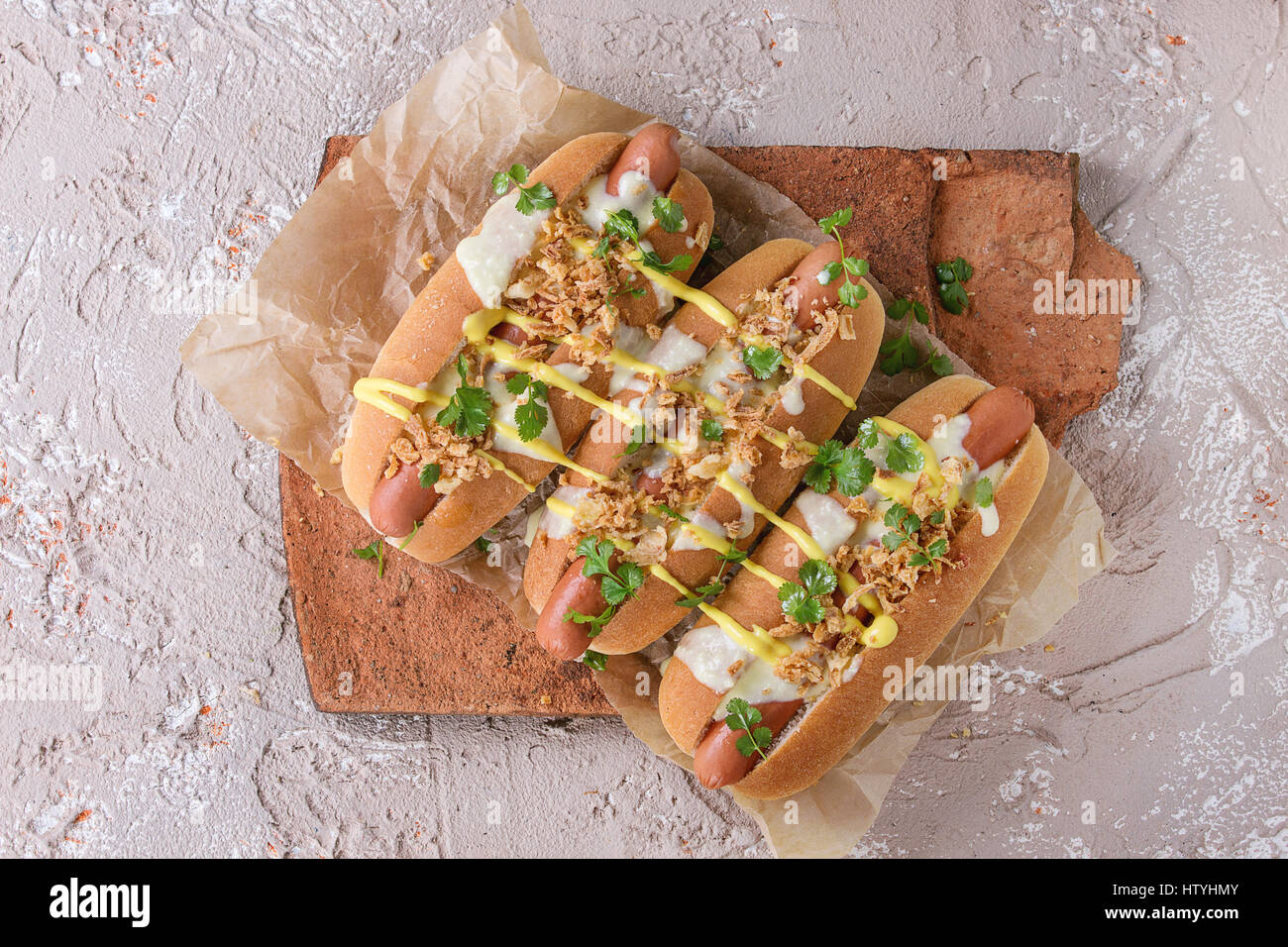 Hot dogs with sausage, fried onion, coriander leaves, cheese sauce and