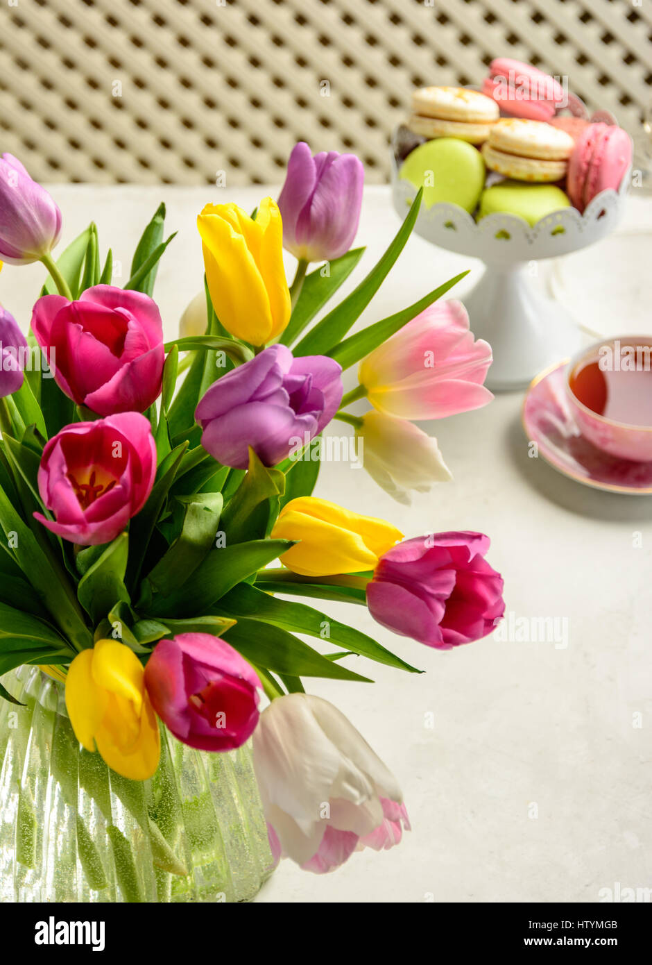Beautiful festive bouquet of tulips and cakes on white background Stock Photo