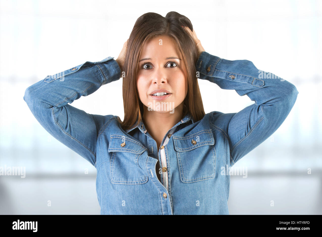 Woman in panic holding her head, in a blue background Stock Photo