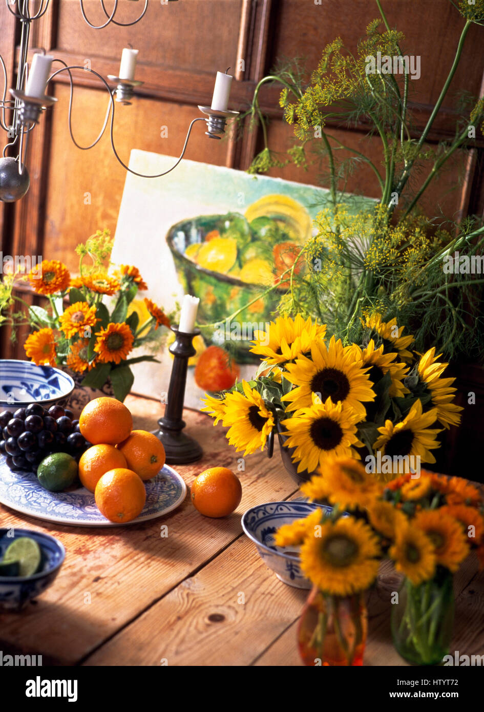 Vases of sunflowers on a rustic wooden table with oranges and grapes ...