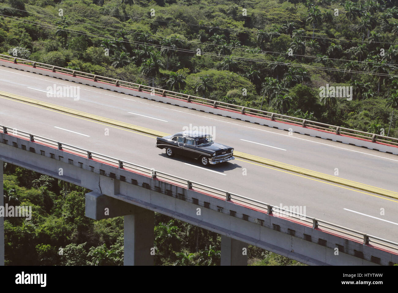 An American style classic car driving across a bridge in Cuba Stock Photo