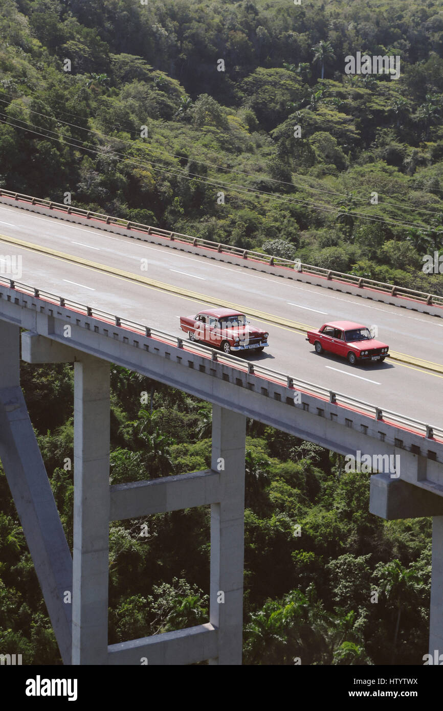 Classic American style cars driving across a bridge in Cuba Stock Photo