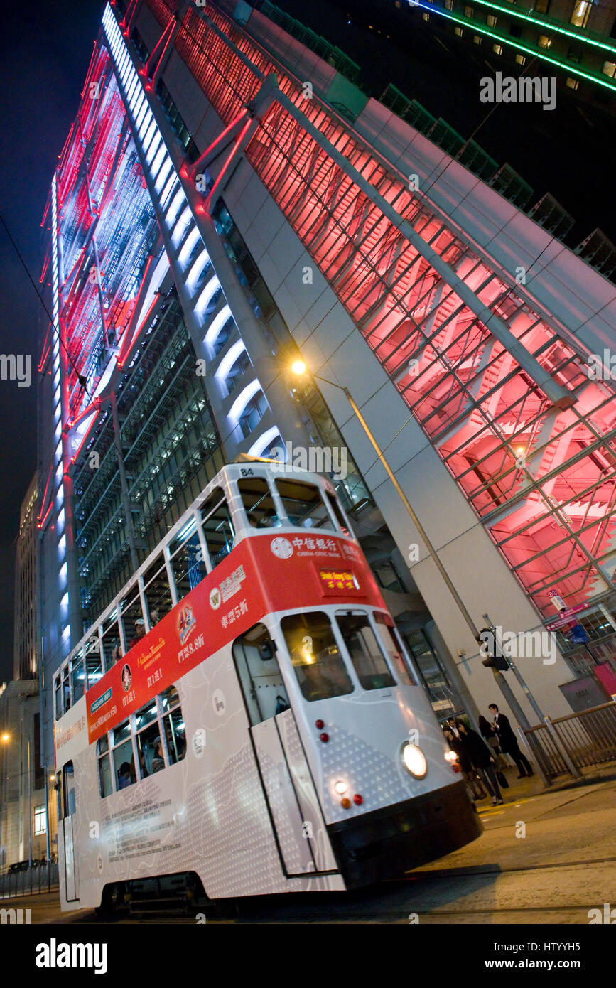 An abstract view of a Hong Kong tram travelling along a street in the business district with skyscrapers in the background at night. Stock Photo