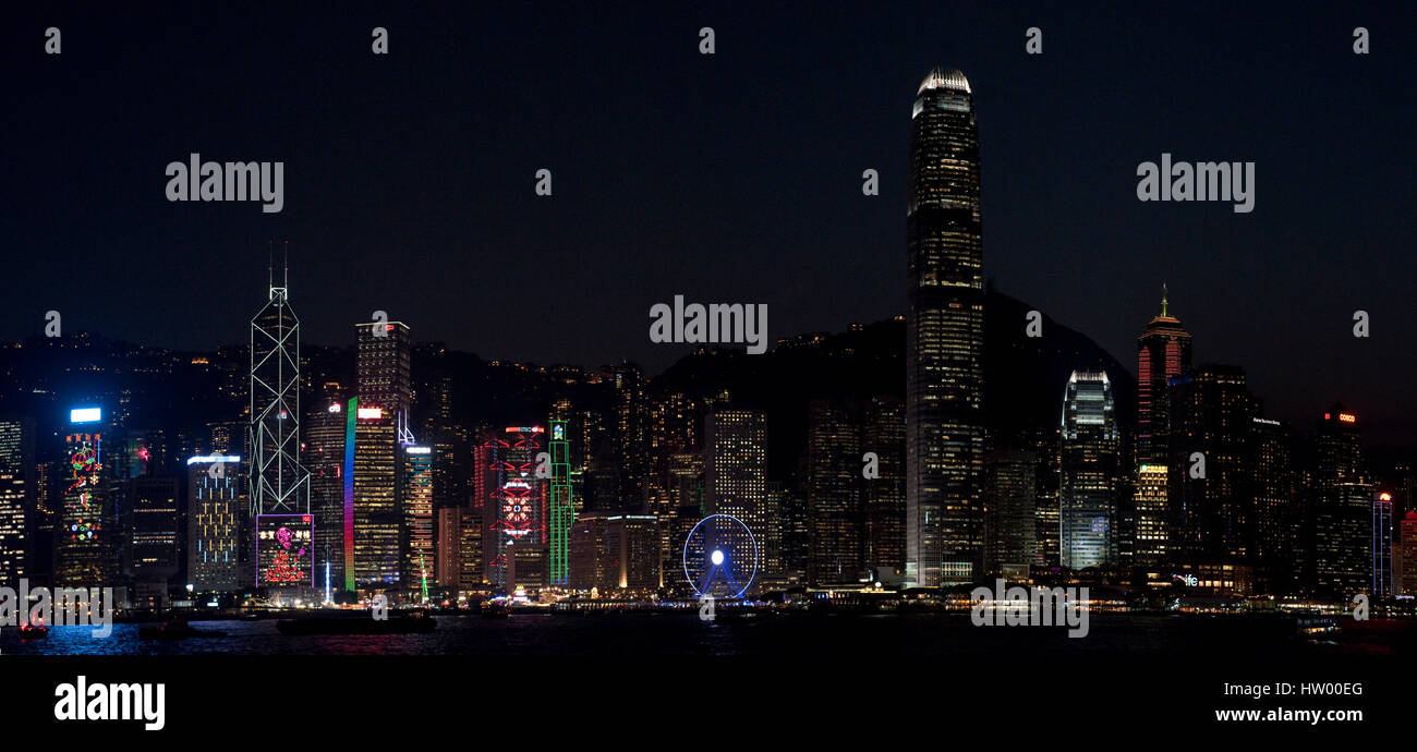 A 2 picture stitch panoramic colourful cityscape view of the buildings along Hong Kong Island from the Kowloon Public Pier at night. Stock Photo