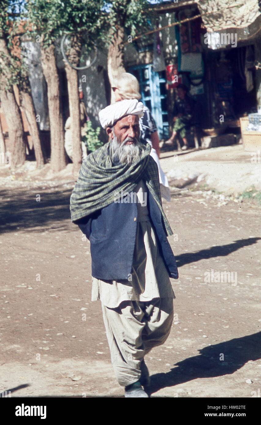 Portrait of an older man in traditional dress walking through the town square in Bamiyan, located in the Hazarajat region of central Afghanistan, November, 1975. Stock Photo