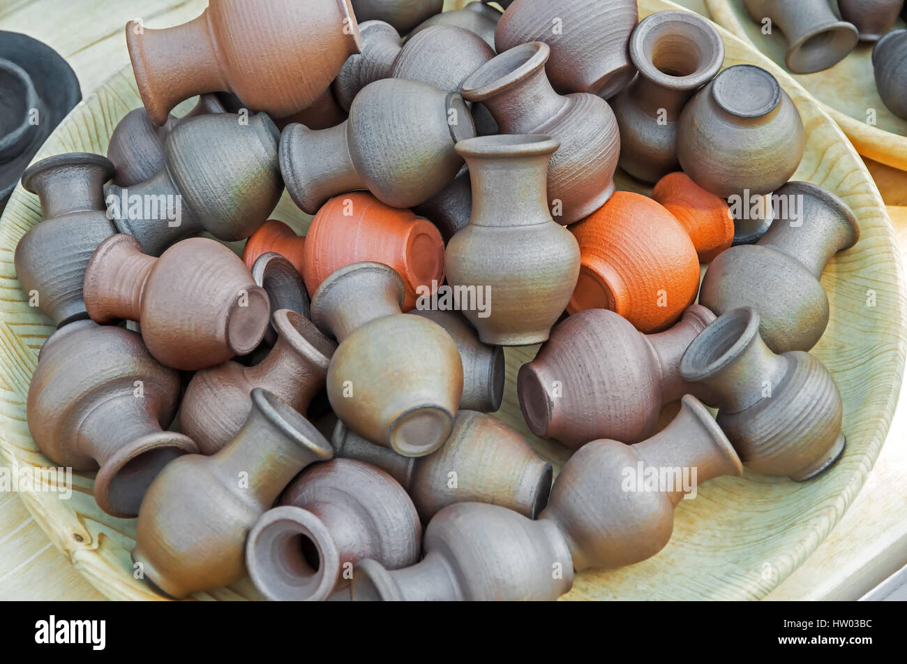 Wooden bowl with a handful of small clay pots and jugs Stock Photo