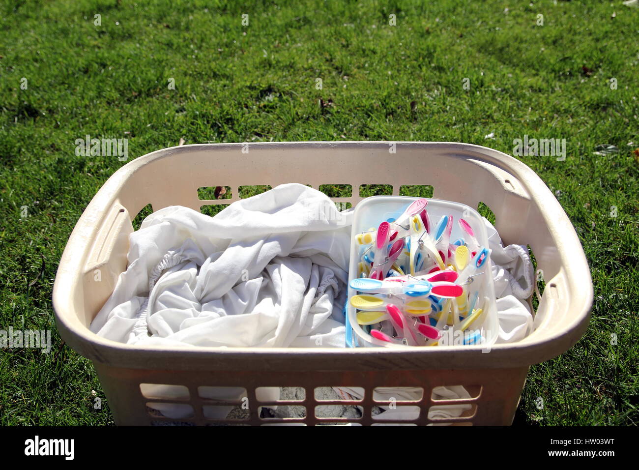 Laundry basket full of laundry ready to be hung out with colorful clothespins Stock Photo