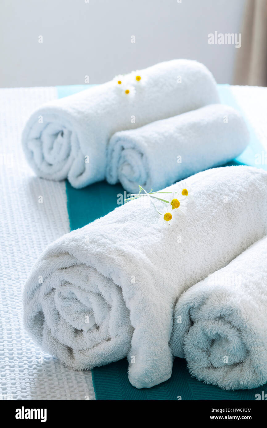 Rolled white towels on bed with flowers Stock Photo
