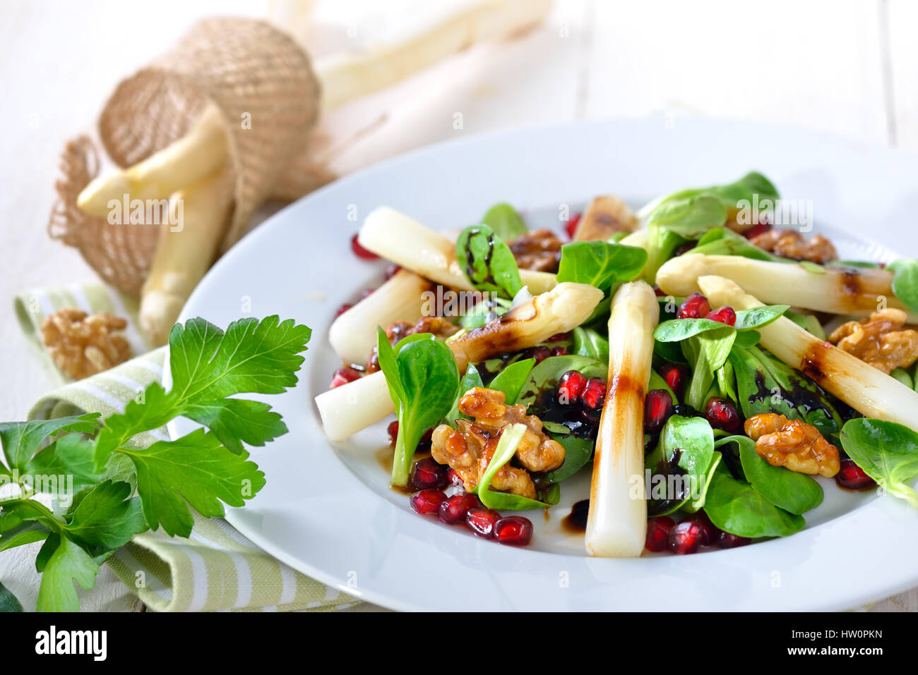 White asparagus on lamb's lettuce with candied walnuts, pomegranate seeds and balsamic vinegar Stock Photo