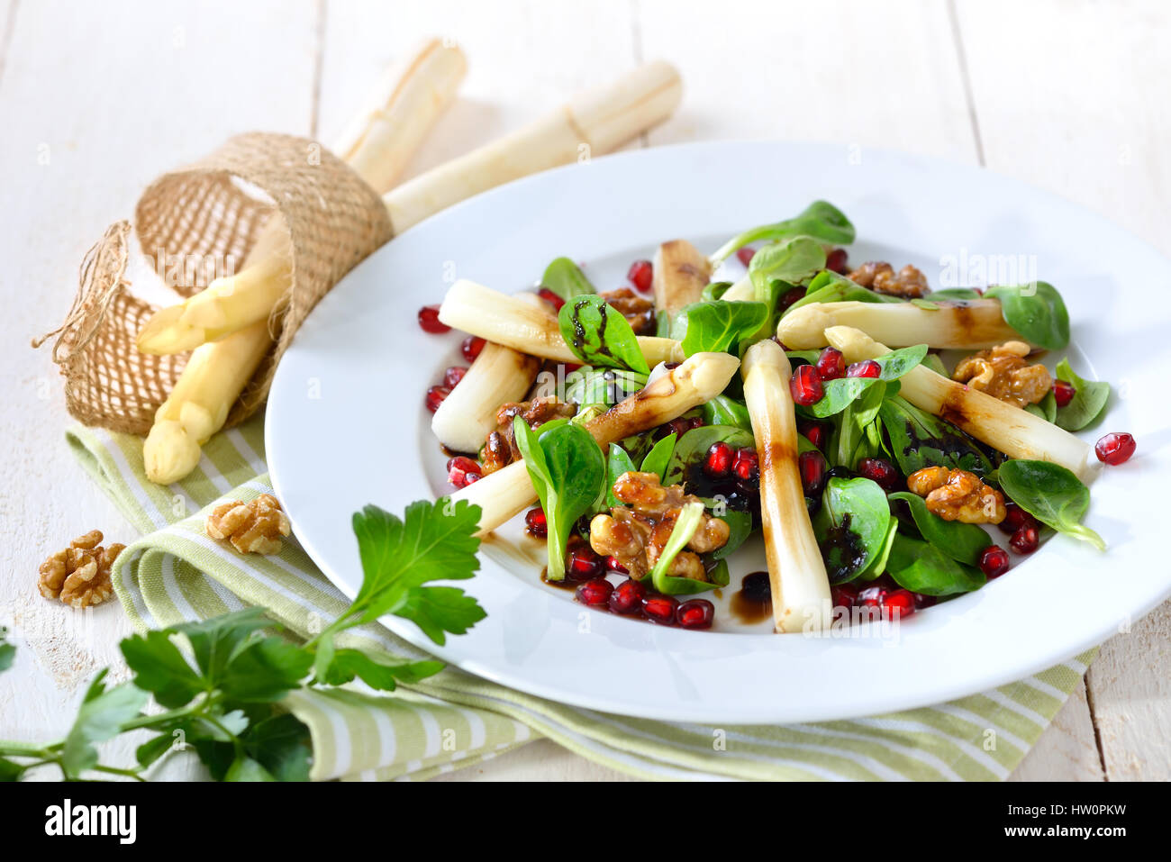 White asparagus on lamb's lettuce with candied walnuts, pomegranate seeds and balsamic vinegar Stock Photo