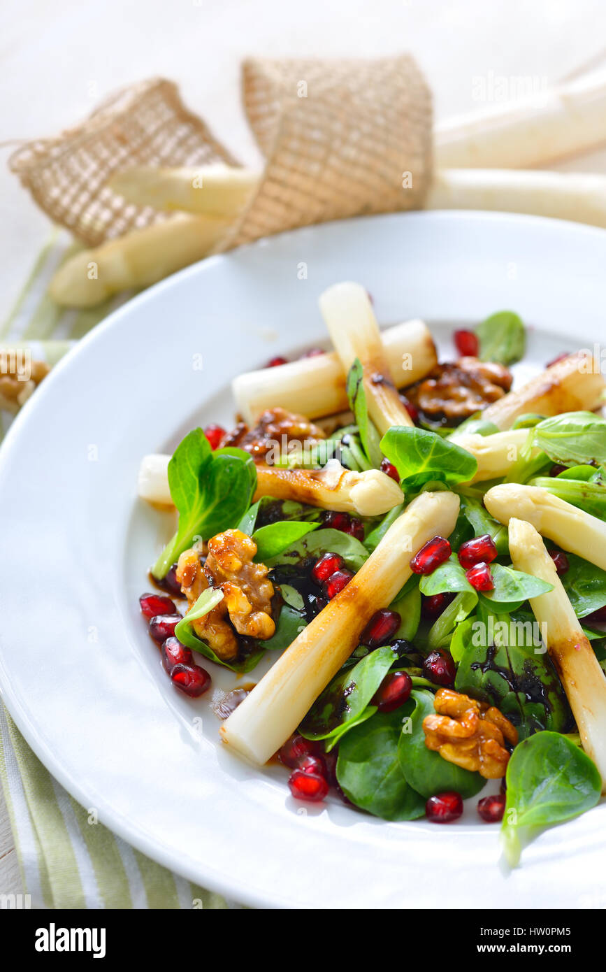 White asparagus on lamb's lettuce with candied walnuts, pomegranate seeds and balsamic vinegar Stock Photo