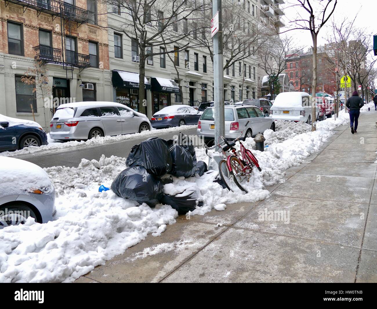 NYC street after Storm Stella. Pedestrians and cars navigate around slush, garbage, and piles of dirty snow. Upper Eastside, New York City, NY, USA Stock Photo