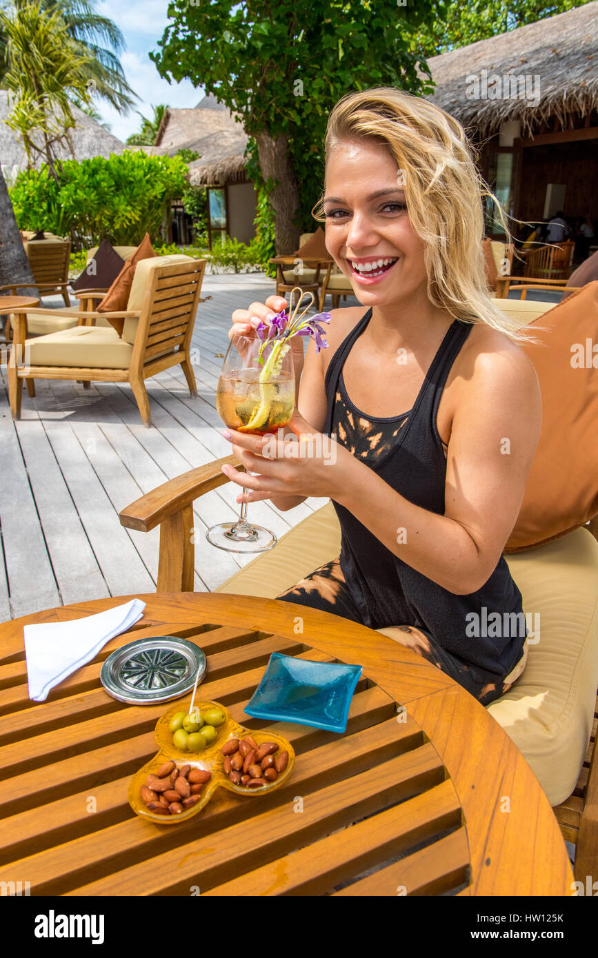 Maldives, Rangali Island. Conrad Hilton Resort. Woman having a drink at the resort (MR). Stock Photo