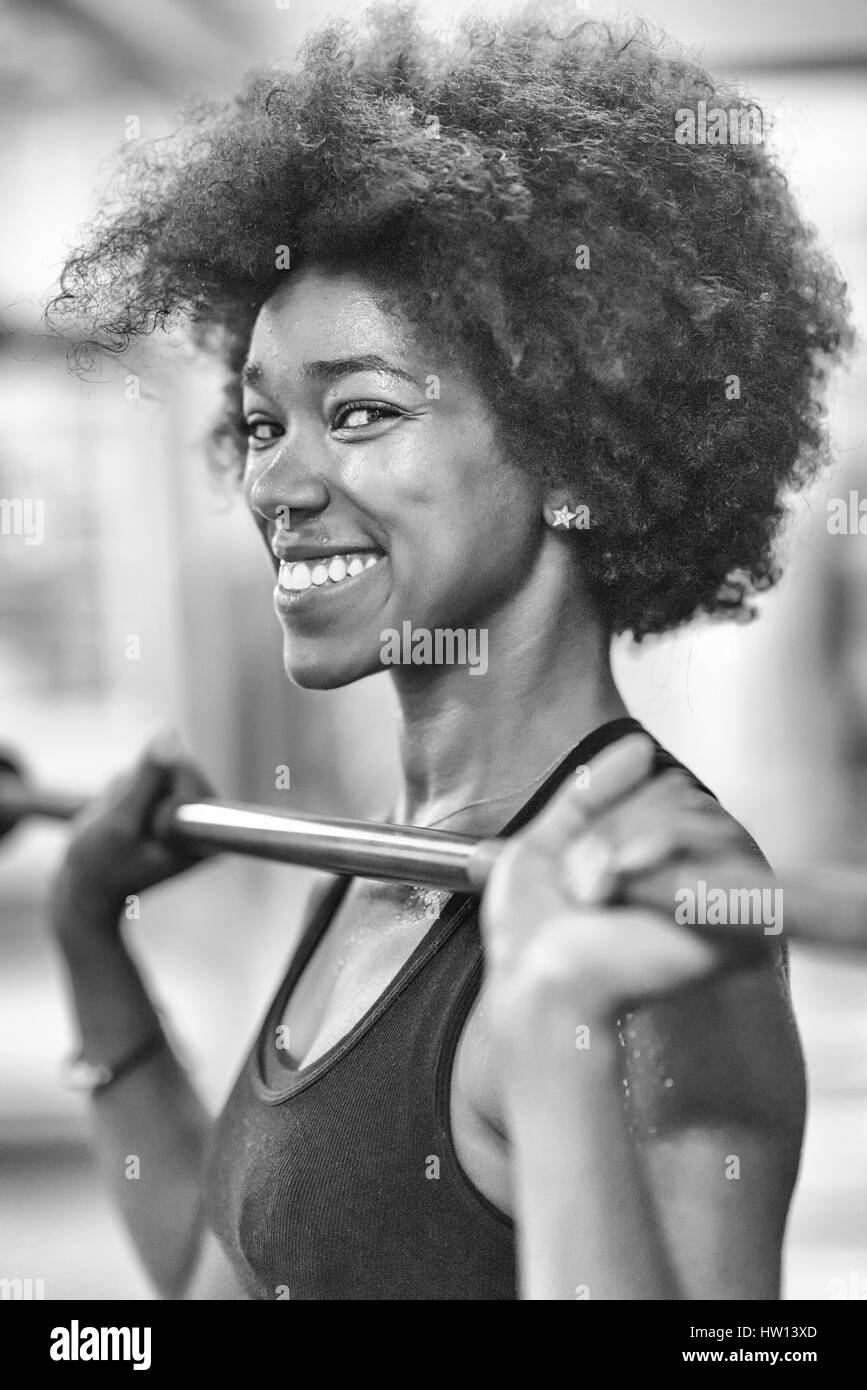 Young Cute african american sport woman in fitness room lifting empty