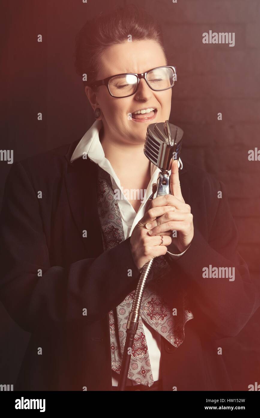Androgynous image of person singing into a vintage microphone Stock Photo
