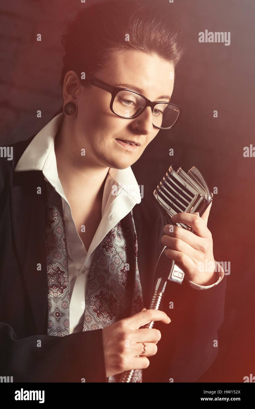 Androgynous concept of person singing into a vintage microphone Stock Photo