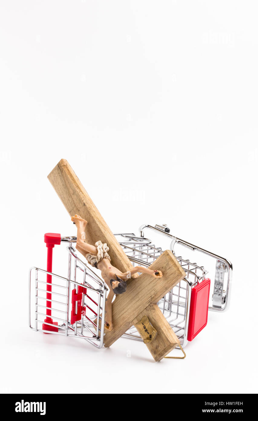 Shopping cart overturned with crucifix on the ground. Conceptual representation of commodification of religion, loss of faith, blasphemy. Stock Photo