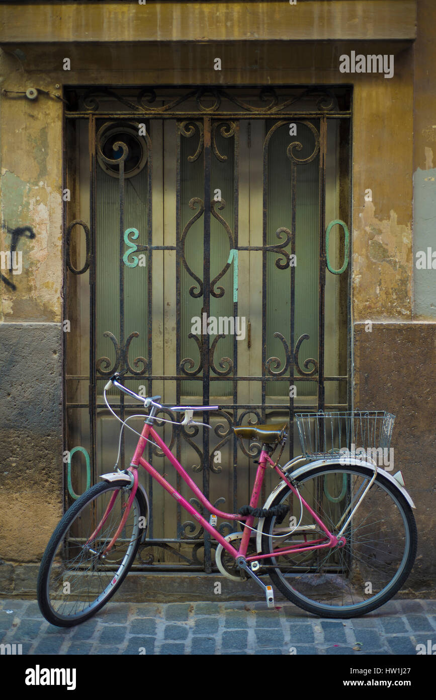 pink bicycle tied on window, at Valencia old town. Stock Photo