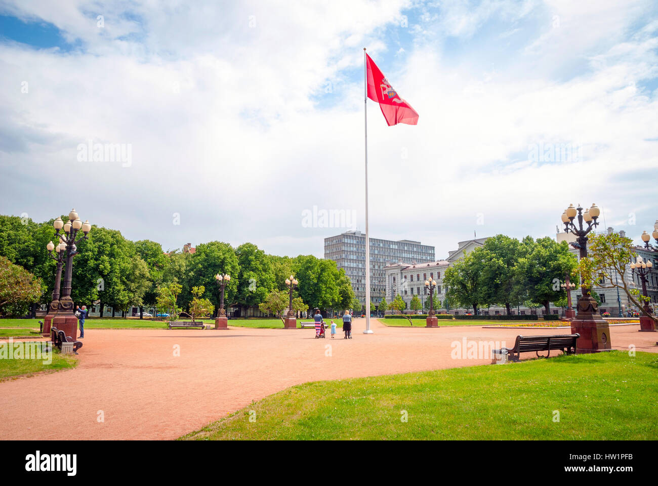 View on red national flag in central park in Vilnius. People walking down. Stock Photo