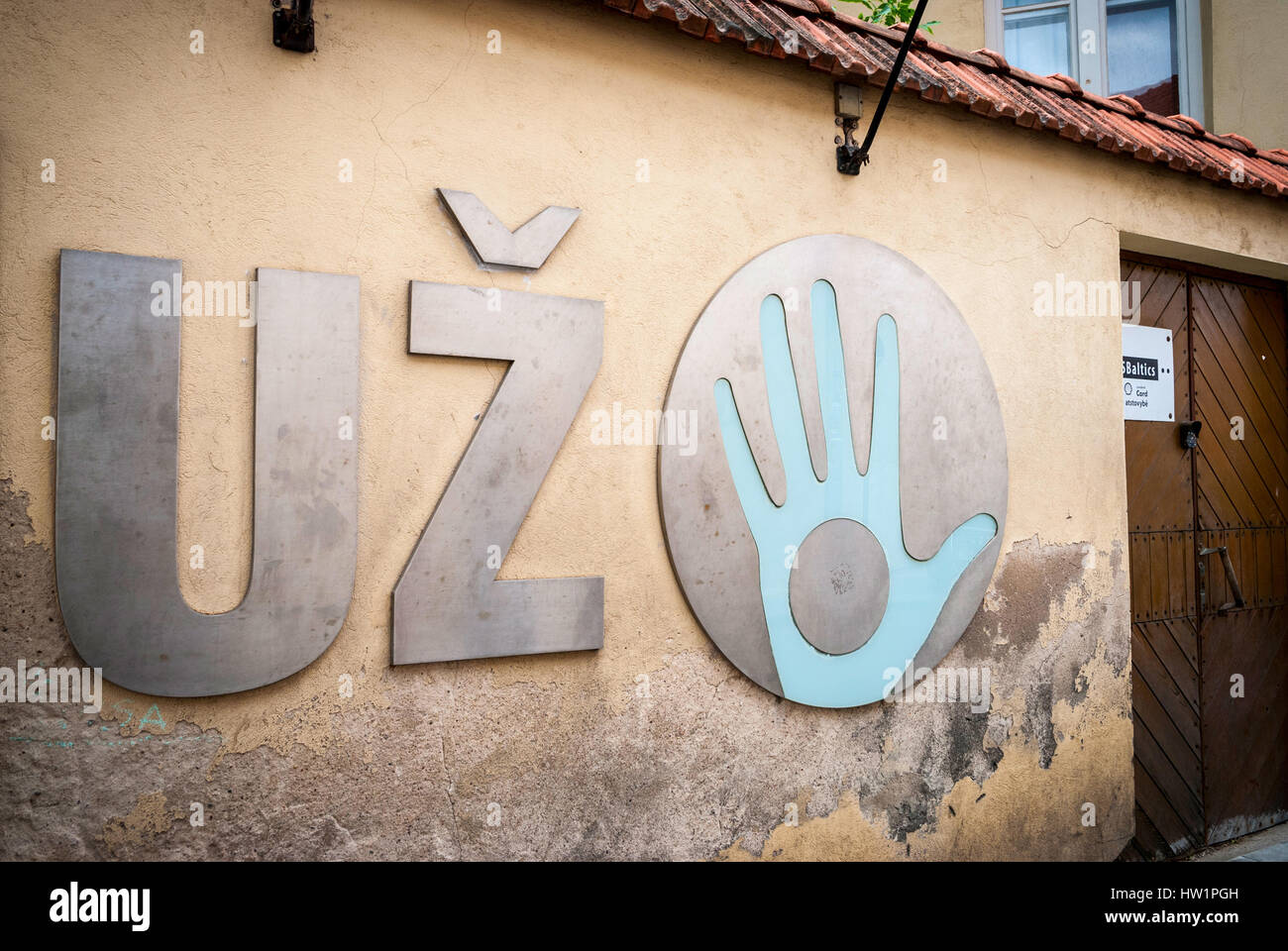 Blue hand on metal circle on cracked wall. Uzupis republic logo, Vilnius, Lithuania Stock Photo