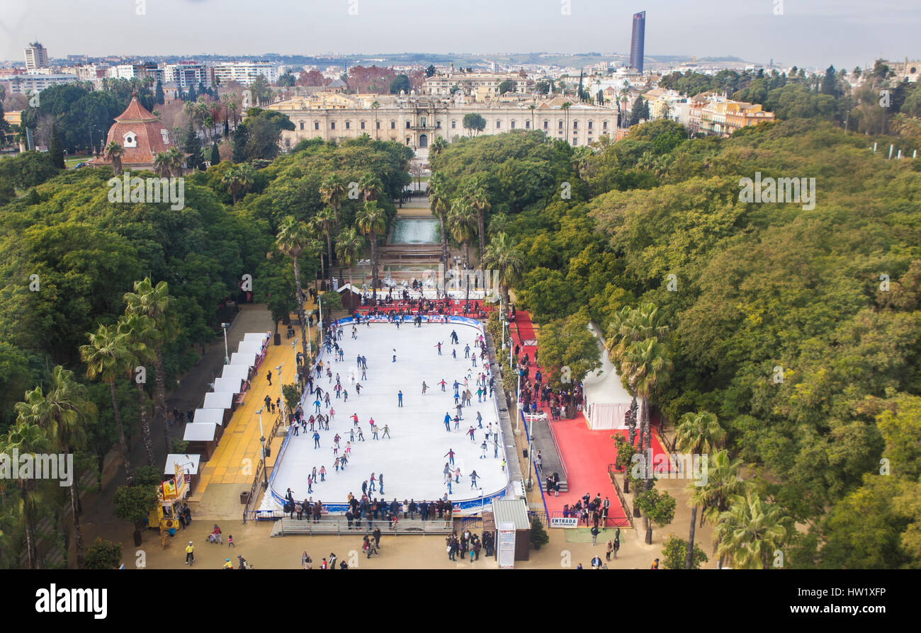 Aerial view from the top of ferris wheel with crowded ice rink and cityscape of Seville, Spain Stock Photo