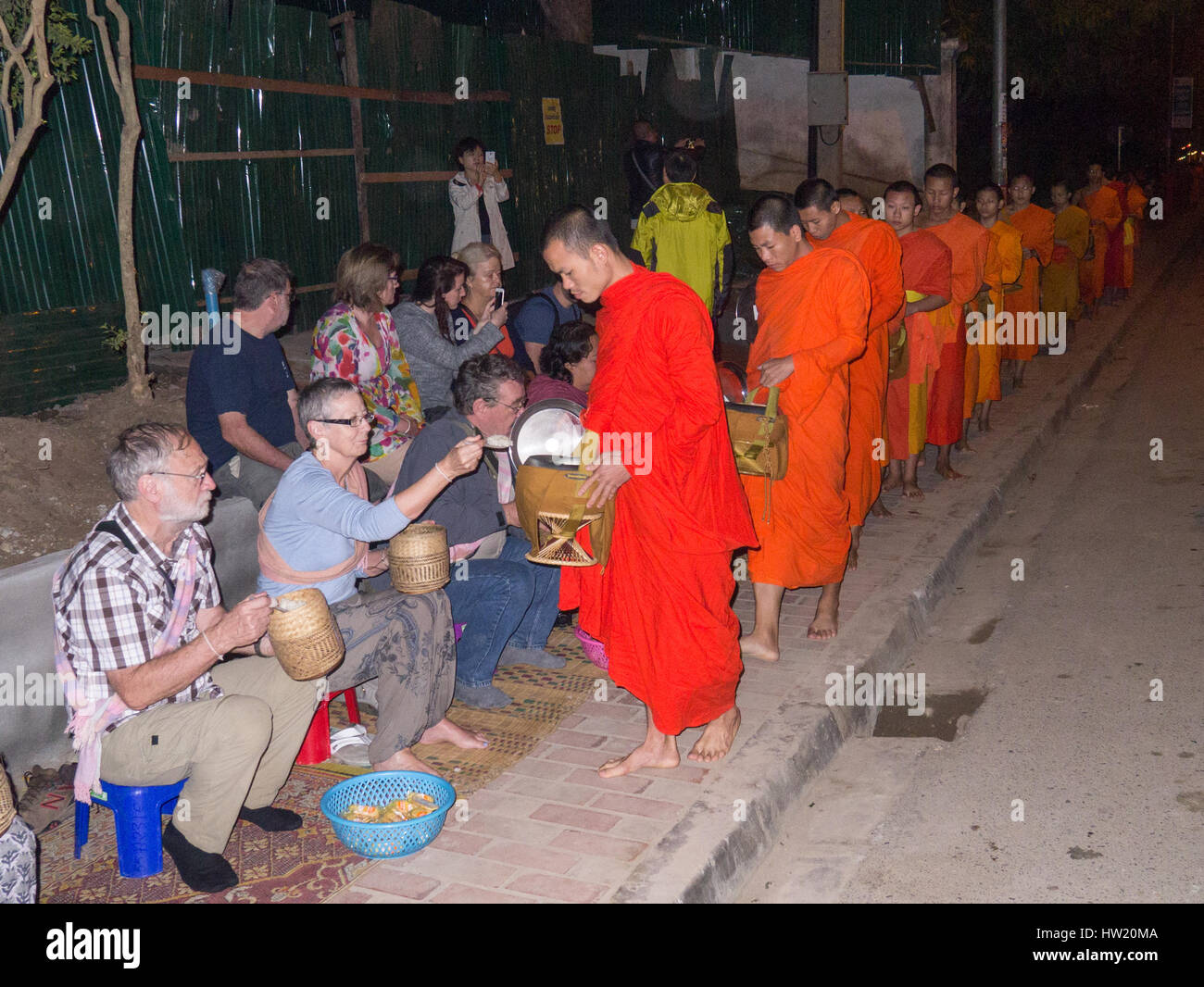 Buddhist monks being given alms by tourists in Luang Prabang, Laos Stock Photo